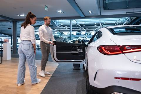 Autohändler und Kundin stehen vor neuem Leasingauto Autohändler und Kundin stehen vor neuem Leasingauto
