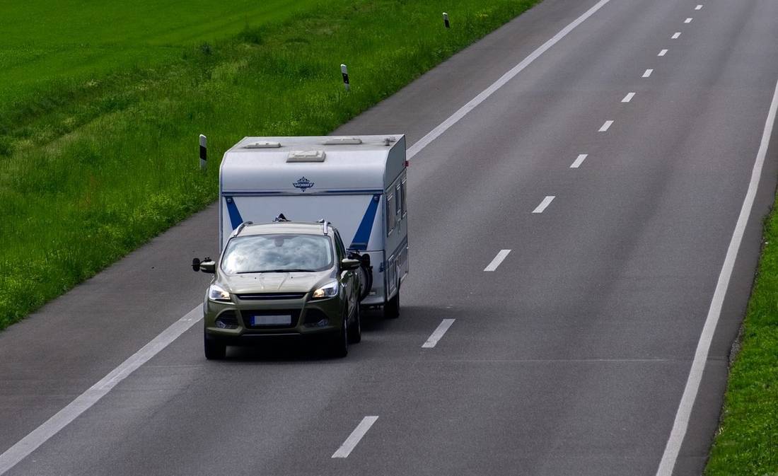 auto mit wohnwagen auf autobahn