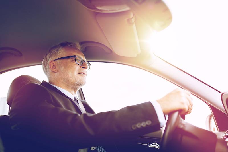 happy senior businessman driving car