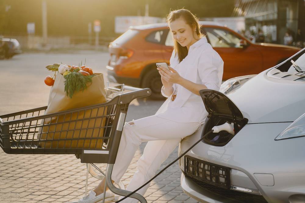 Woman charging electro car at the electric gas station