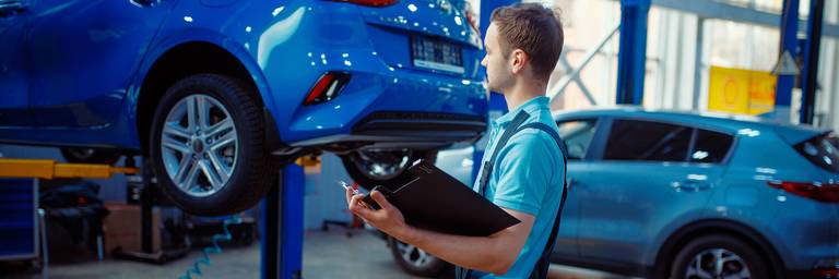 mann prüft auto bei hauptuntersuchung