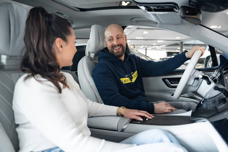 Frau und Mann sitzen lachend im Auto