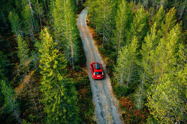 Aerial view of red car with a roof rack on a country road in Finland