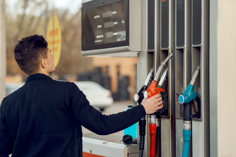 mann nimmt zapfpistole an tankstelle