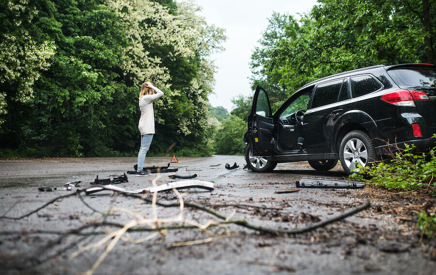 frau steht vor auto mit schaden