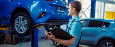 mann prüft auto bei hauptuntersuchung