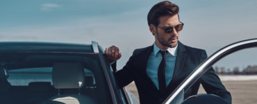 geschäftsmann steigt in firmenwagen ein