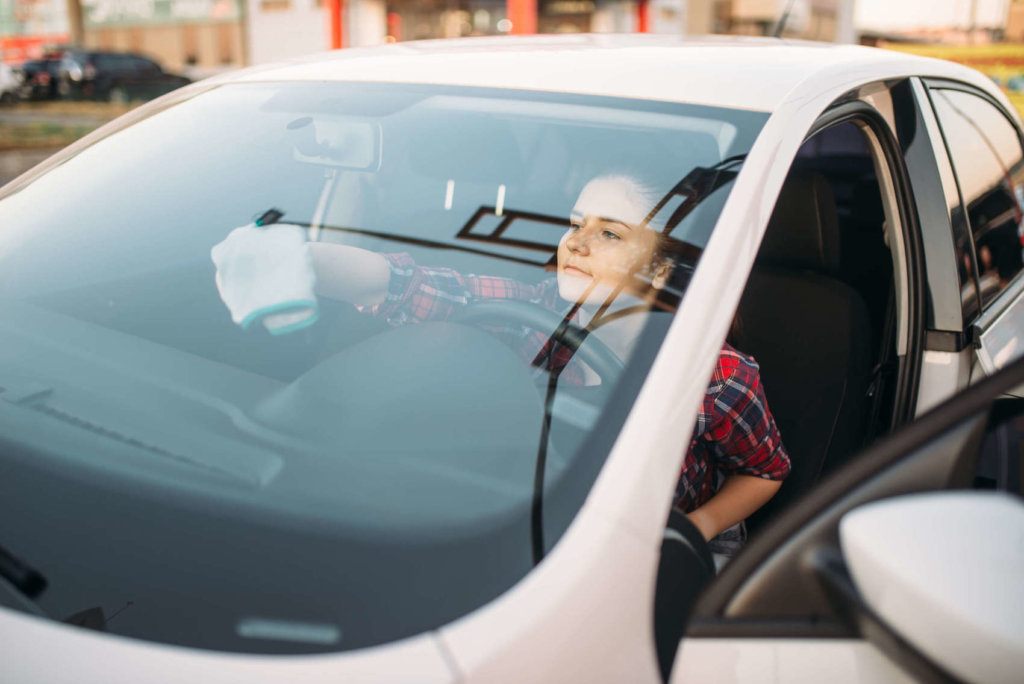 frau reinigt autoscheiben von innen