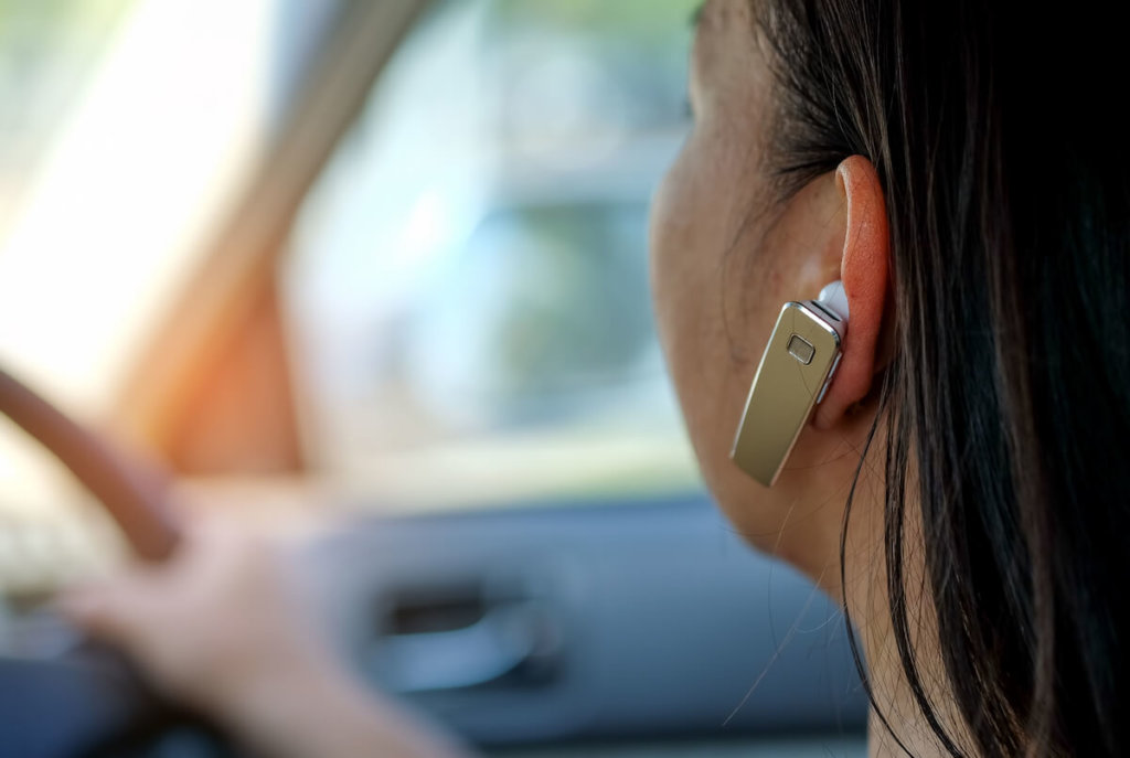 frau im auto mit einem headset für eine freisprechanlage