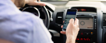 mann mit handy am steuer