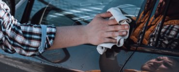 mann putzt und poliert autoscheiben