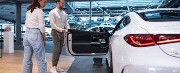 Autohändler und Kundin stehen vor neuem Leasingauto